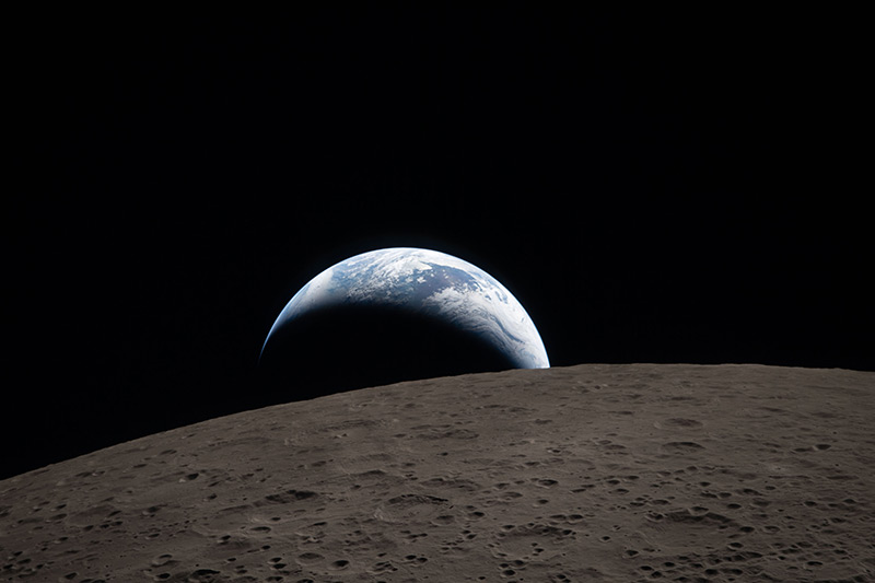 A color photograph of Earth setting behind the moon.