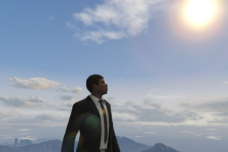 A man in a suit looking at the sun with a distant view of a city in clouds.