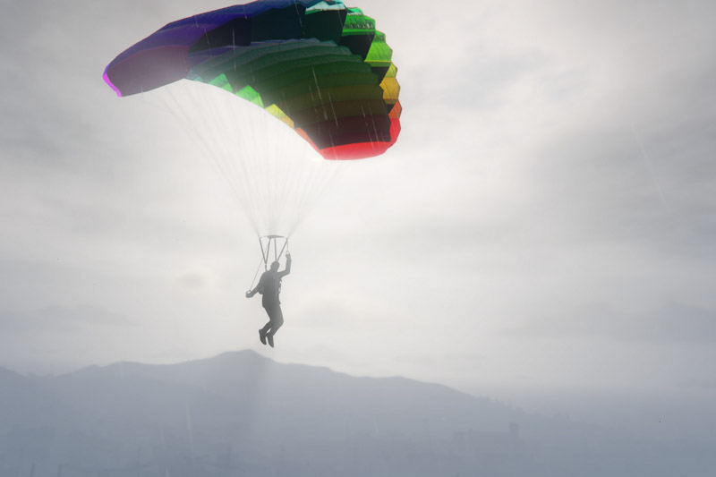 A man in a suit gliding with a rainbow-colored parachute.